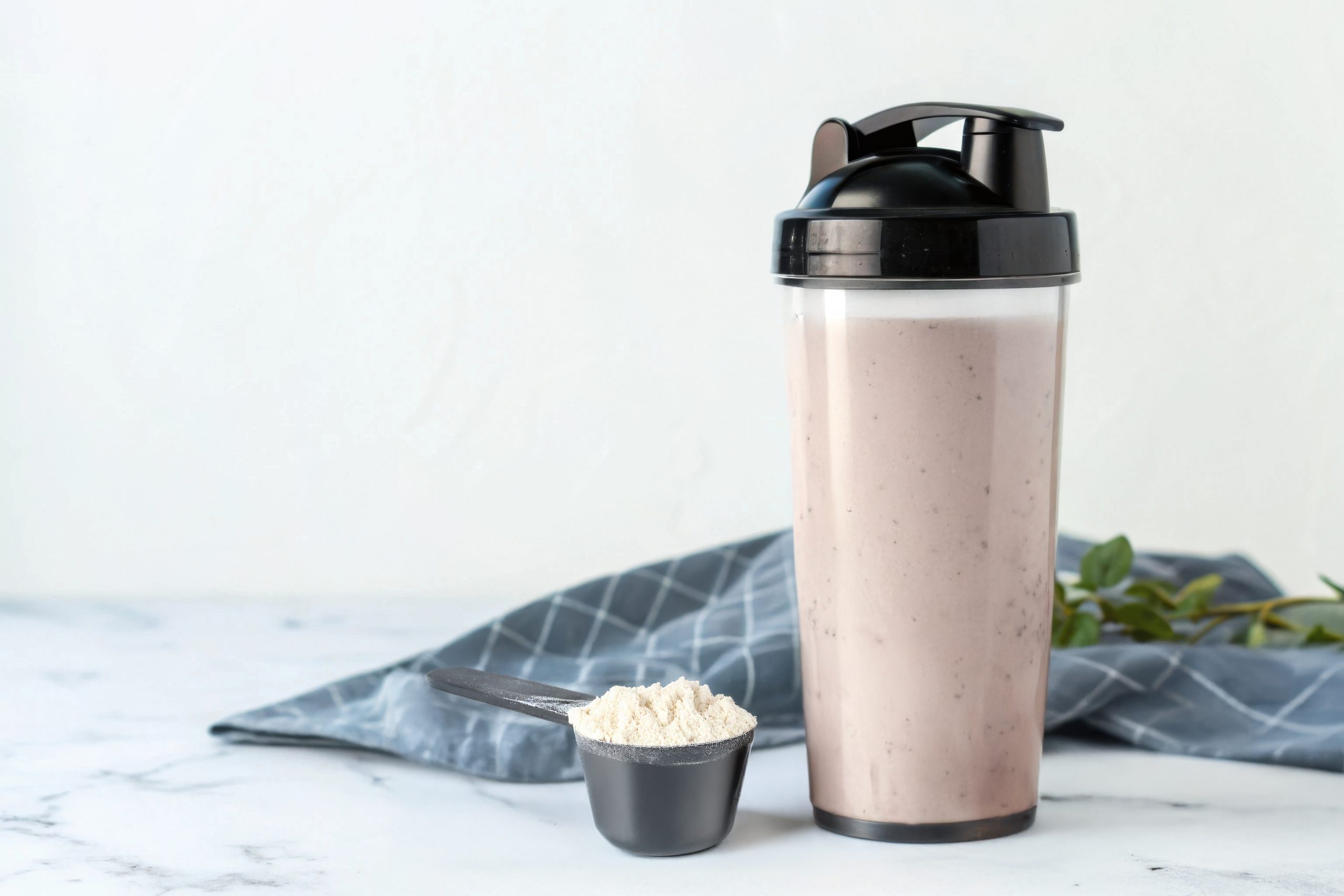 sleek-shaker-bottle-filled-with-protein-shake-supplement-scoop-marble-table
